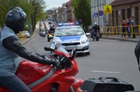 mężczyzna na motorze, na dalszym planie ulicą jedzie radiowóz policyjny a za nim kolumna motocykli