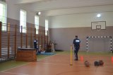 sala gimnastyczna, na której widać dwóch policjantów oraz mężczyznę w stroju sportowym wykonującego ćwiczenie z piłka lekarską